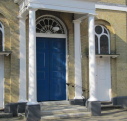 8  recessed round-headed windows either side of main door